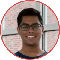 a man in glasses smiling in front of a brick wall